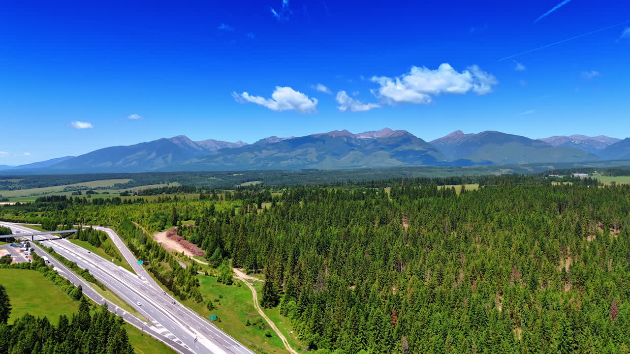 Roads cross the wildlife nature landscape of Slovakia. Spectacular Tatra mountains at backdrop. Aerial view