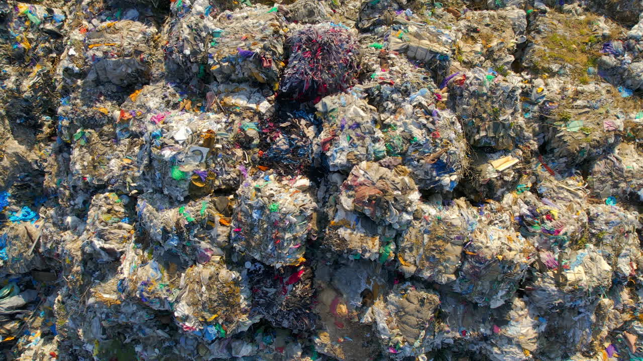 Drone view of huge heaps of pressed garbage at waste sorting plant. Slow motion