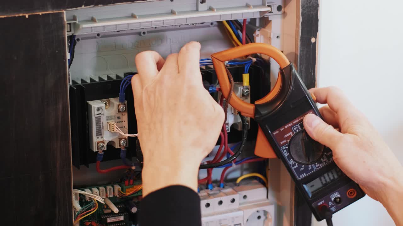 los electricistas ponen las manos a probar la corriente eléctrica en el panel de control. el ingeniero electricista trabaja midiendo el voltaje y la corriente de la línea eléctrica en el control del gabinete eléctrico.