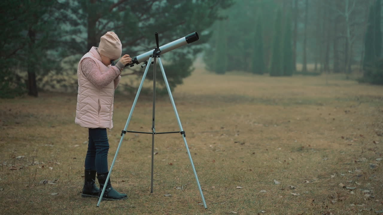 숲에서 망원경을 통해 보는 작은 소녀