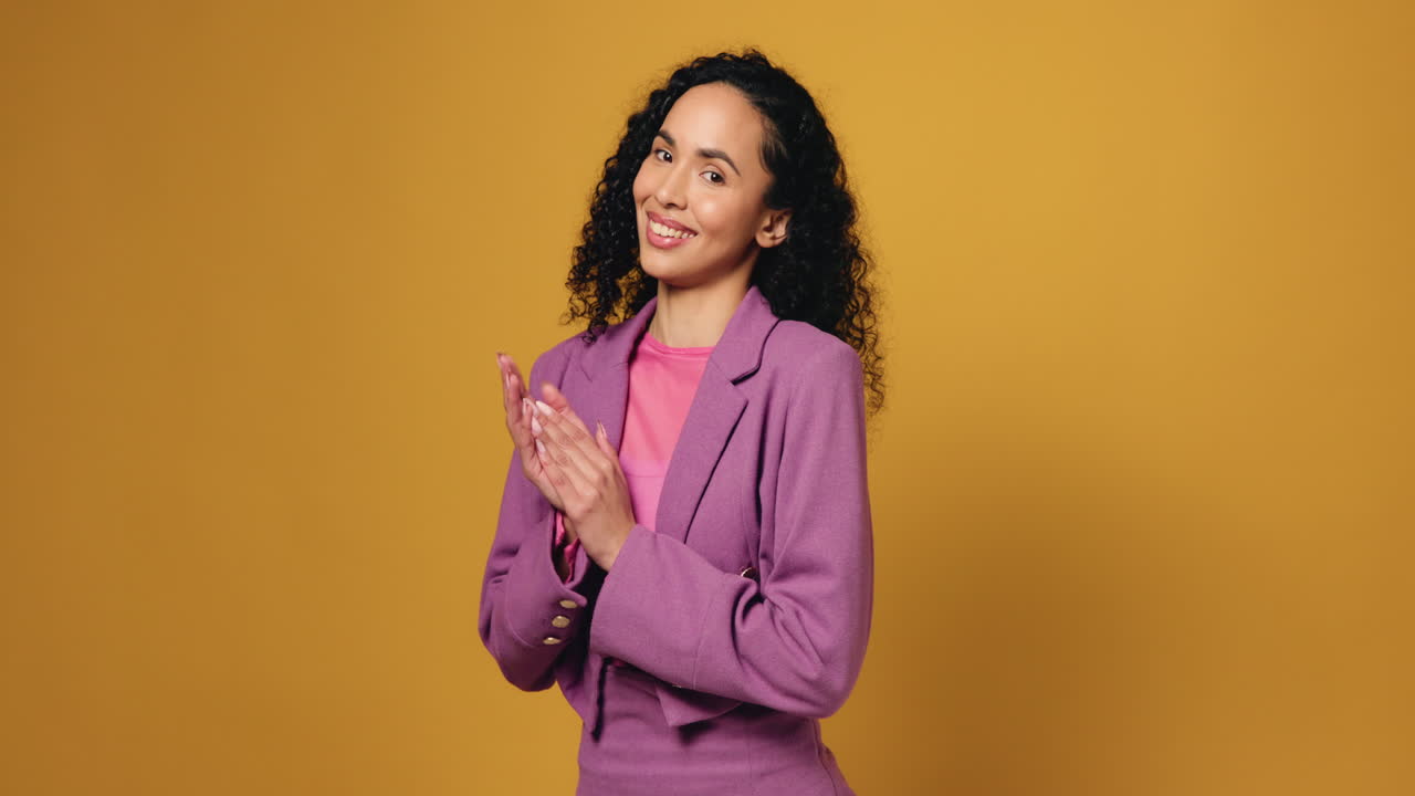 Donna in tailleur rosa che applaude su sfondo giallo