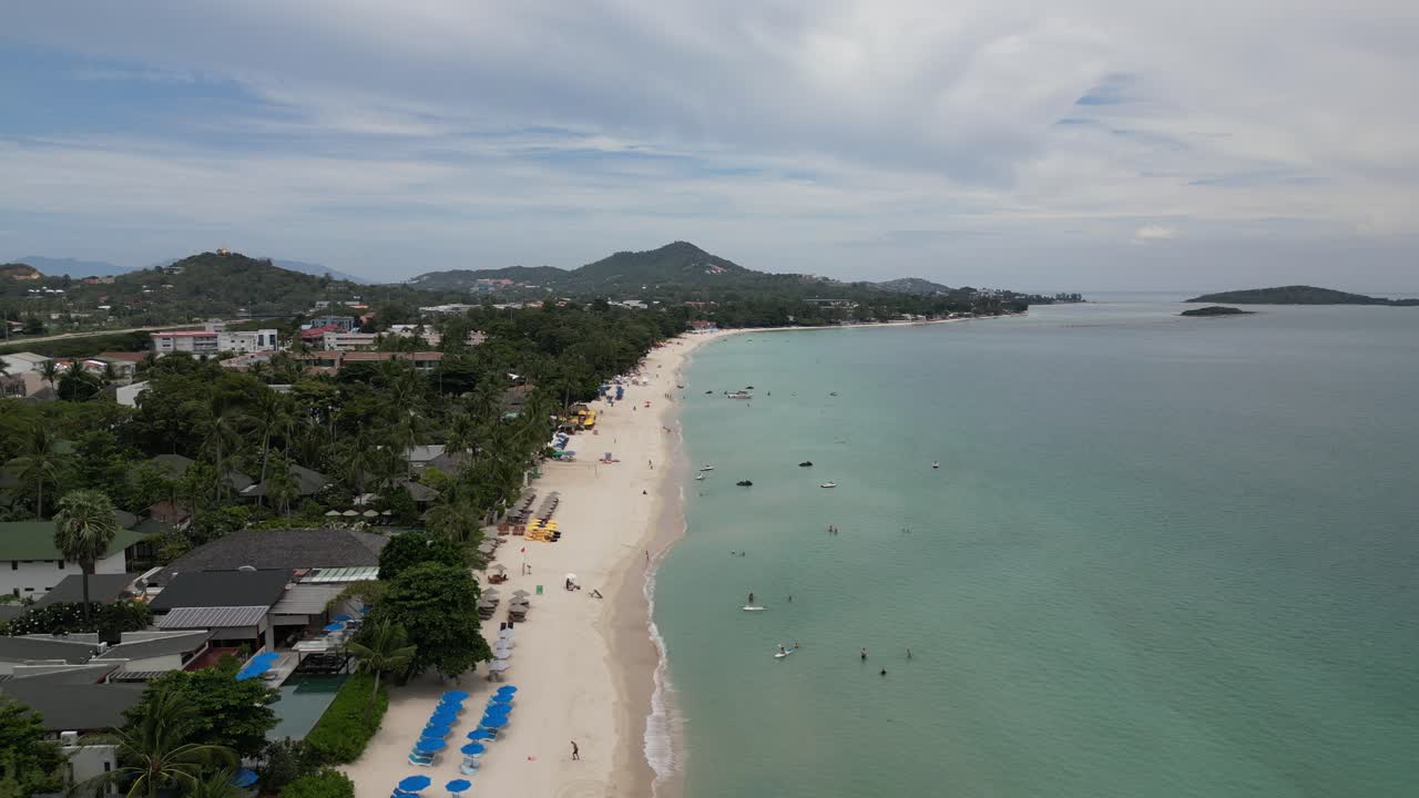 bird view of a posh beach tide in short luxurious spot for tanning celebrities adventure holiday area wealthy people houses clear water blue vibrant vivid mountains in the background little island sky