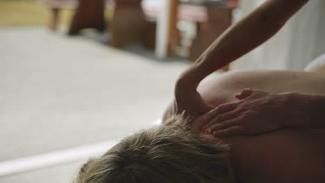 professional hands performing shoulder massage on young blonde woman with dowager's hump