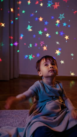young child looking at colorful star projections on a wall
