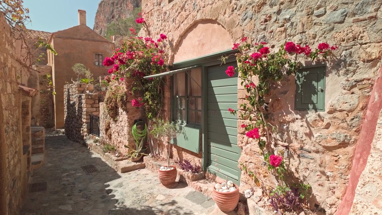 Fiori rossi mediterranei su un'incantevole strada medievale in ciottoli di pietra a Monemvasia