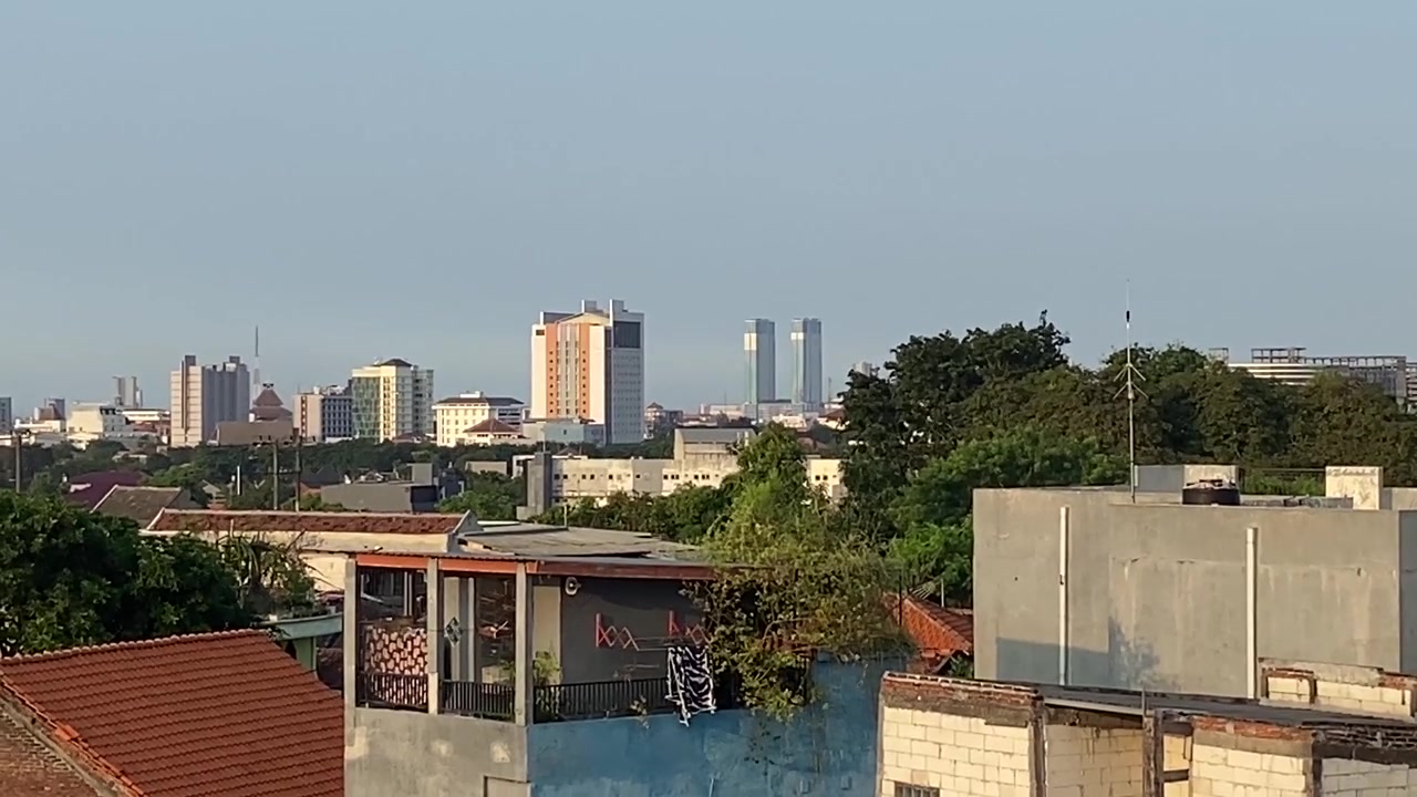 Cityscape View with Residential Rooftops and Modern Buildings Against a Clear Sky