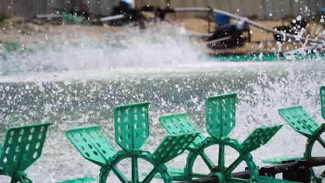 water splashing from green paddle wheel aerators on a shrimp farm at son hai, vietnam