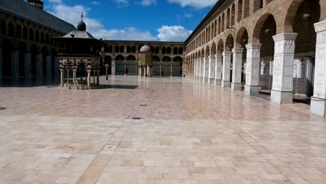 view of inside the courtyard of the umayyad mosque in syria. drone is flying from the inner courtyard of the mosque, where we see the building exterior inside the mosque, to the outside of the mosque.