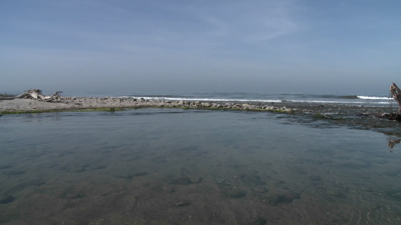 panorámica del hombre caminando por el agua en el estuario del río ventura en el punto de surfistas en ventura california
