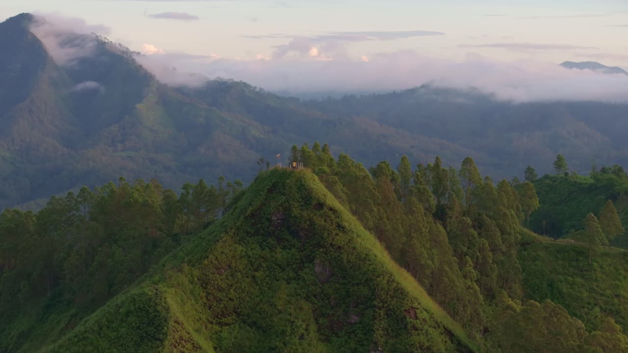 Puncak Gunung Inerie bersinar di atas hutan hujan saat fajar, Flores, Indonesia