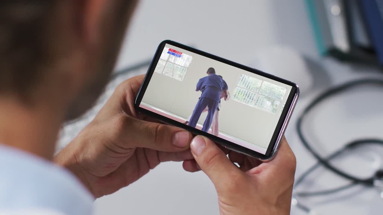 Männlicher Arzt schaut Judokampf auf dem Smartphone