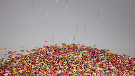 vibrant sprinkles cascade onto a growing pile against a neutral background, captured in slow motion for a dynamic visual effect
