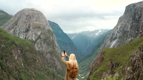 woman taking a photo of a norwegian fjord