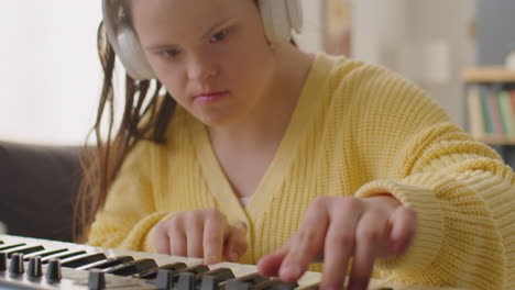 girl with down syndrome playing synthesizer with wireless headphones