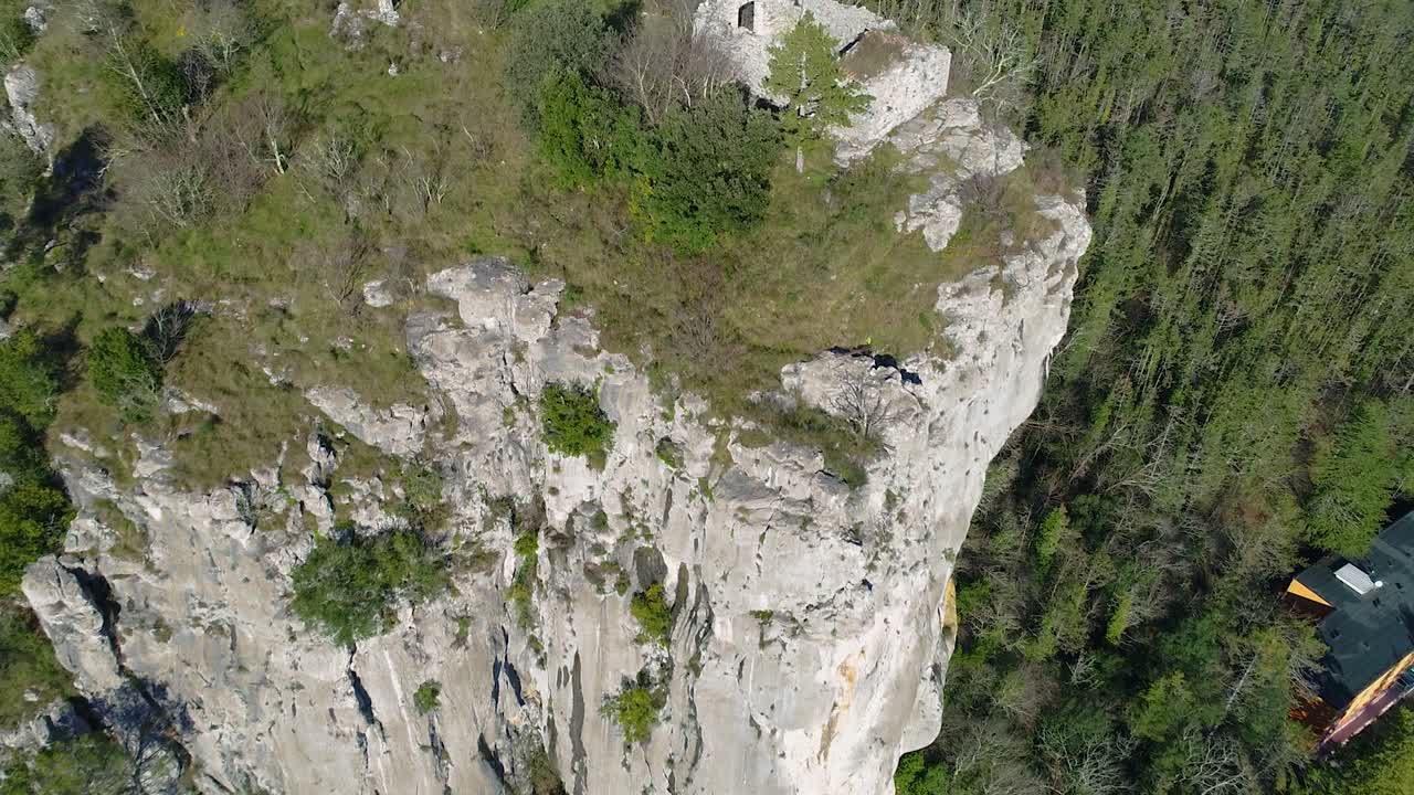 Rock cliff vertical wall. Forest, ruins and religion crosses on top. Fly over