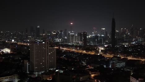 a nighttime time lapse shot of cards driving down a bustling freeway in bangkok, thailand