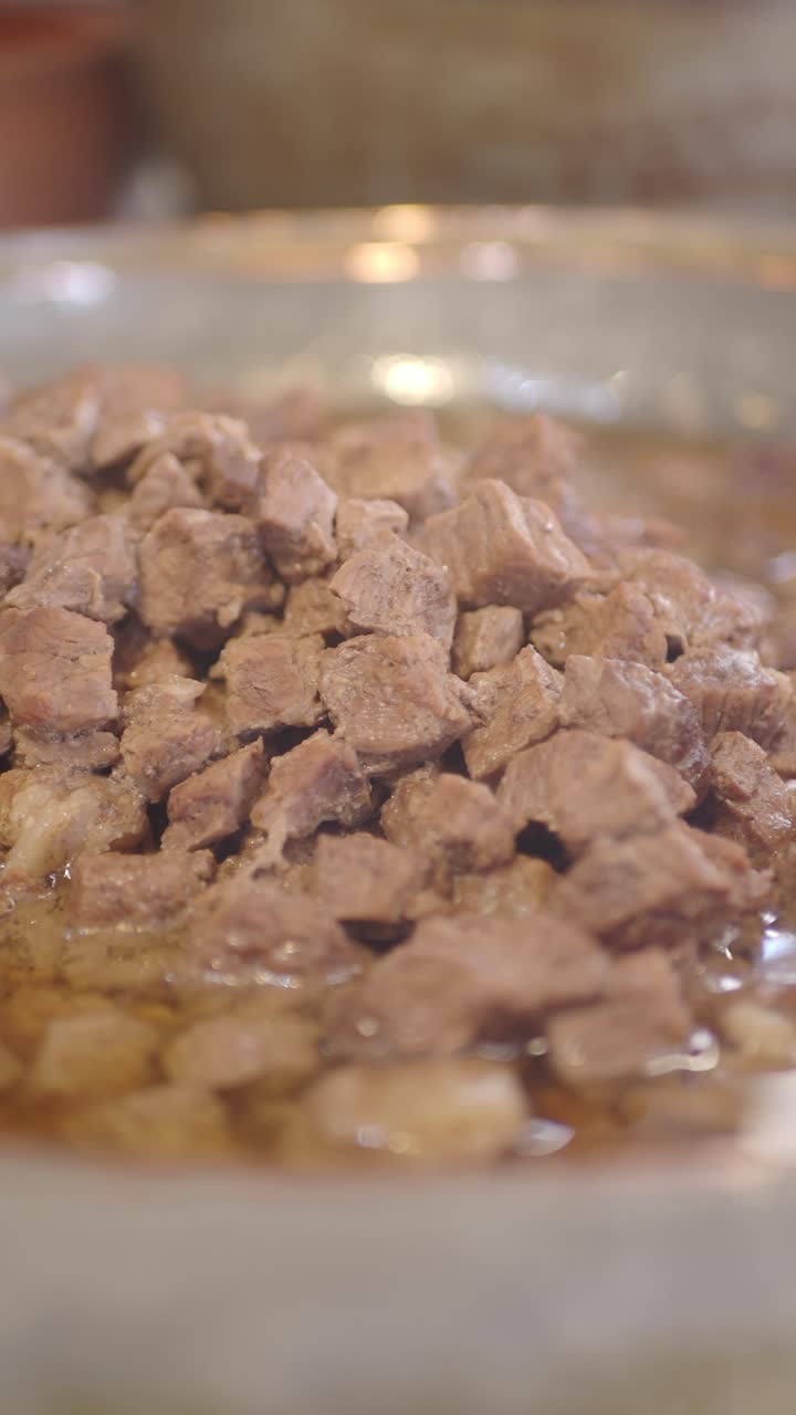 Nahaufnahme von gewürfeltem Fleisch, das in einem Topf köchelt.