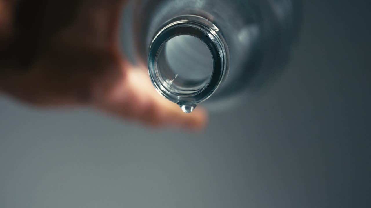 caída de gota de agua de una botella de vidrio vacía, cámara lenta, mostrando la importancia de la hidratación para una vida saludable, alta velocidad, macro