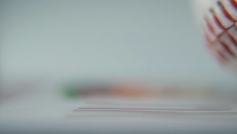 cinematic commercial macro shot of a rotating white base ball, close-up on red stitches, baseball rotate, professional studio lighting, smooth slow motion 120 fps