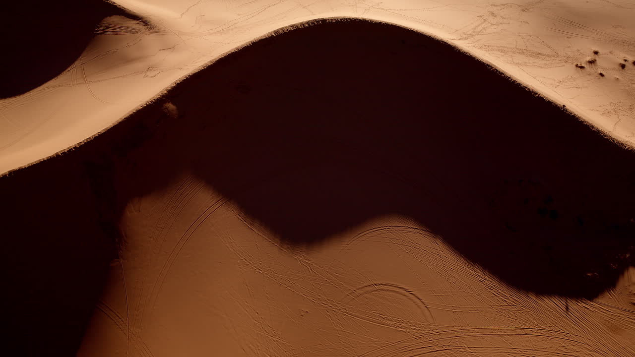 Mesmerizing forms and vibrant shades swirl through the pink sand dunes in this surreal aerial shot.