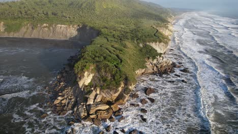 point elizabeth lookout in new zealand - rugged coastline with crashing waves, rocky cliffs, and vegetation. aerial orbiting shot