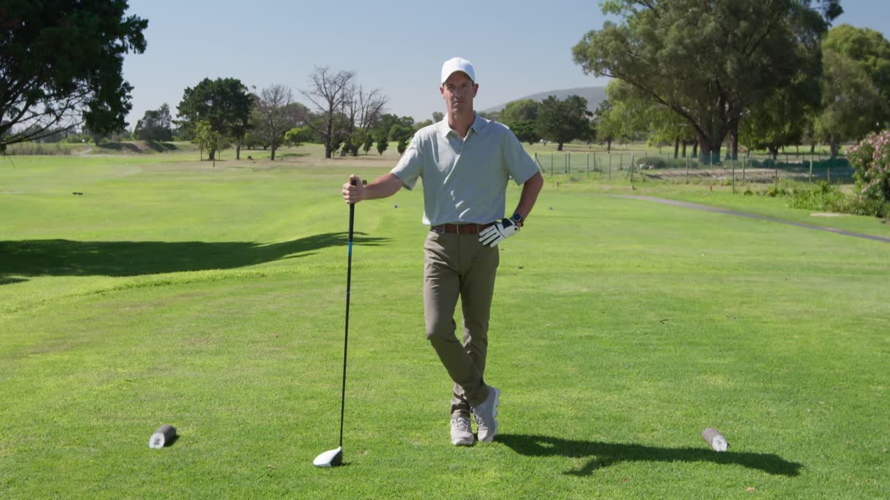 Golfista maschio caucasico che sorride alla telecamera su un campo da golf