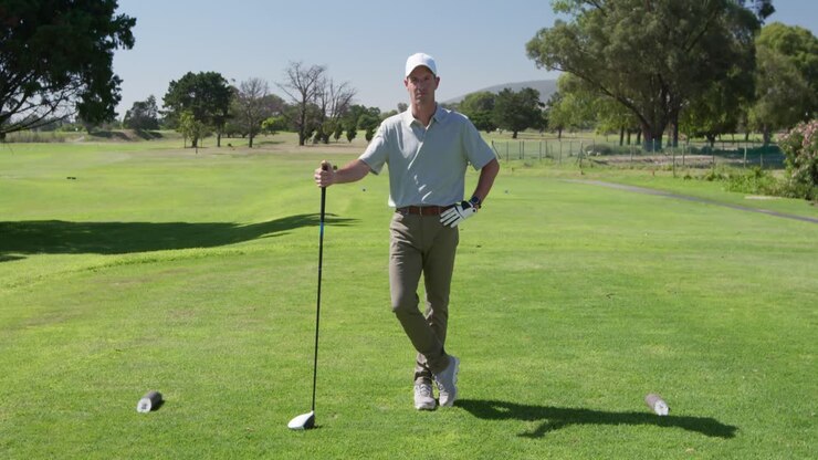 Golfista maschio caucasico che sorride alla telecamera su un campo da golf