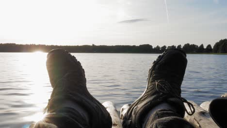 man wearing black shoes lying on a wooden raft by the lake in prądzonka, poland - closeup shot