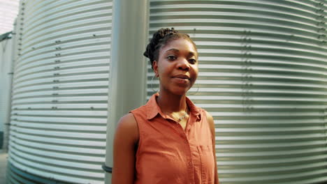 portrait of african american woman by water storage tank in greenhouse
