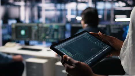 close up of data center software developer using tablet to review code