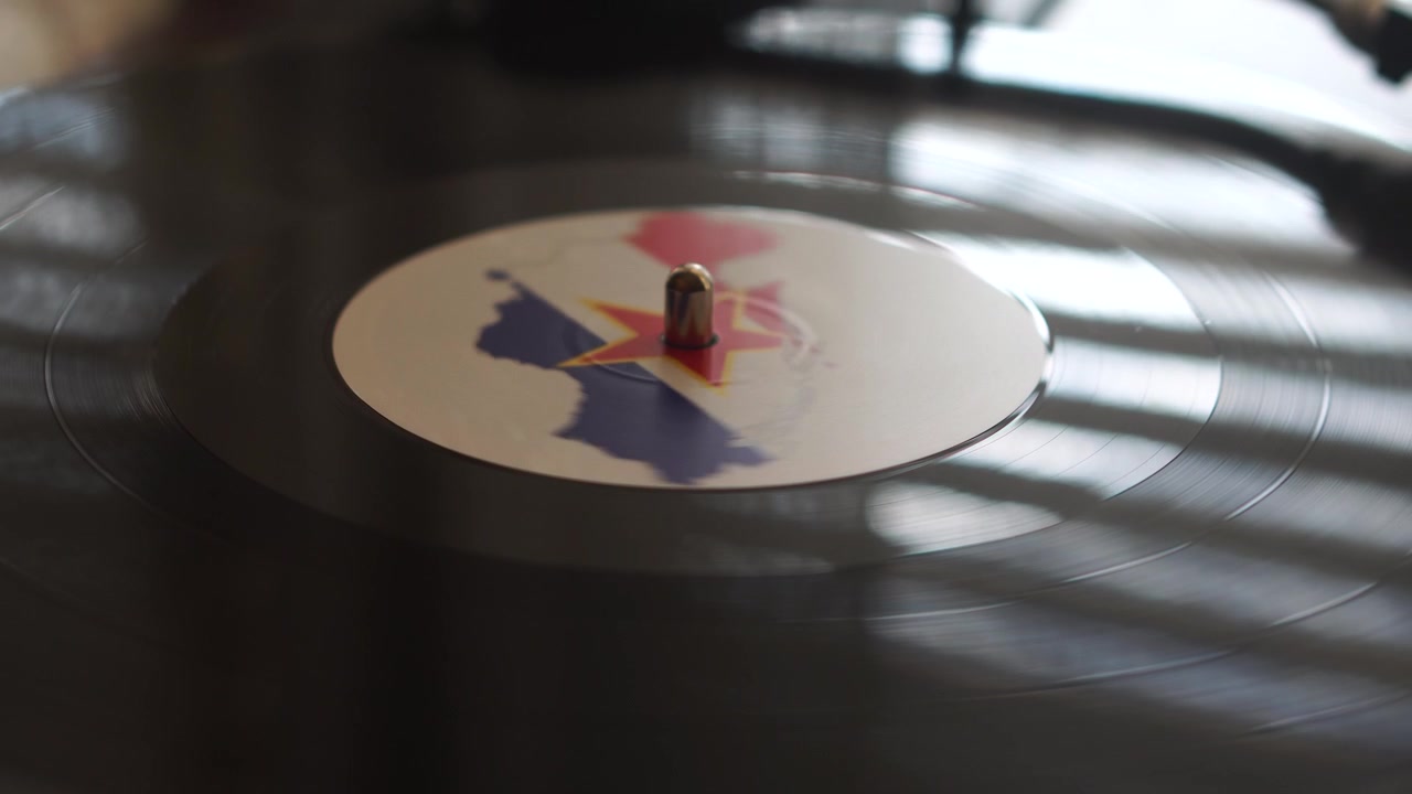 Riproduzione di un disco in vinile con mappa e bandiera della Jugoslavia, compilazione musicale ex-jugoslava.