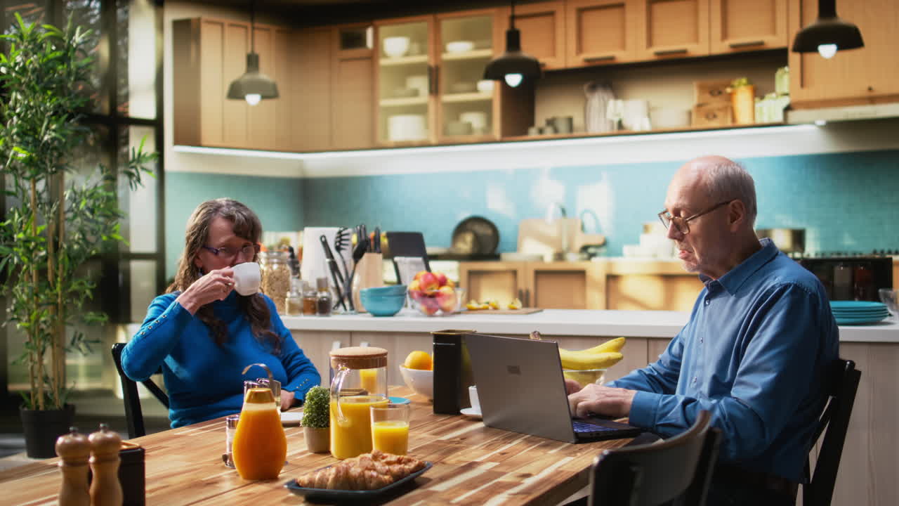 Elderly husband and wife enjoying morning routine at breakfast table