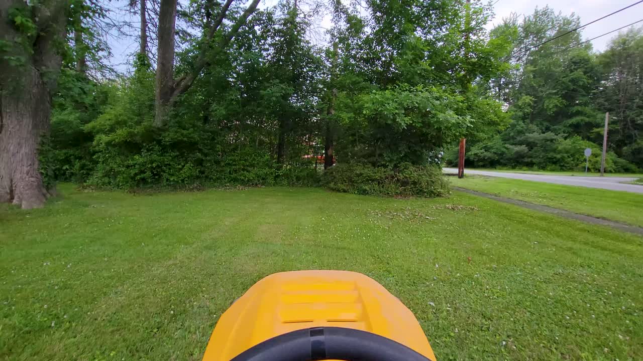 POV footage of a lawn mower cutting grass with a hand on the wheel, perfect for gardening, landscaping, and outdoor lifestyle projects.