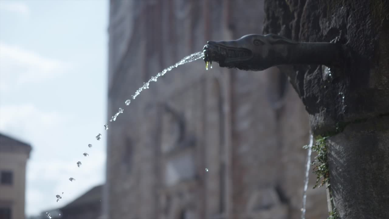 Historical and ancient water fountain spout releasing arched stream of water, Italy.