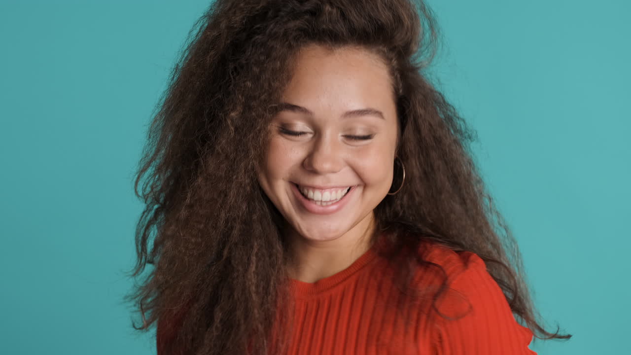Caucasian curly haired woman smiling to the camera.
