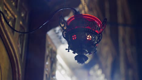 Orthodox-church-lamp-with-lit-candle-in-red-glass,-establishing-shot