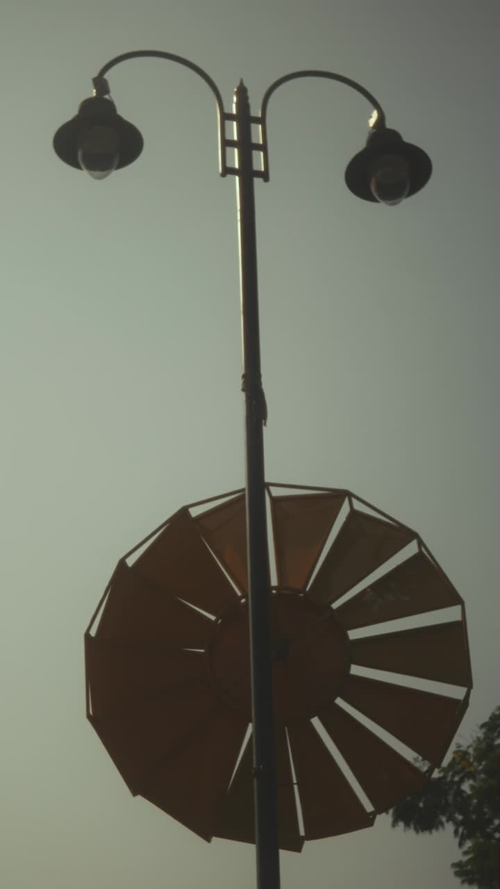 Streetlamp and windmill silhouetted against a clear sky, peaceful mood