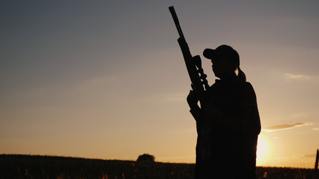 una mujer con un arma cruza el campo al comienzo de la temporada de caza disparo de steadicam