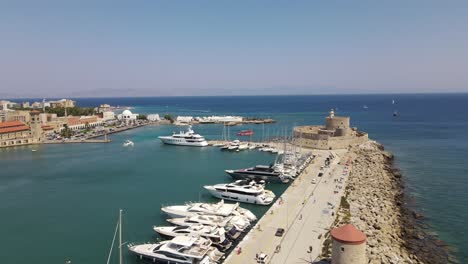 Lighthouse-and-medieval-fortress-Saint-Nicholas-in-Rhodes-marina,-aerial-orbit