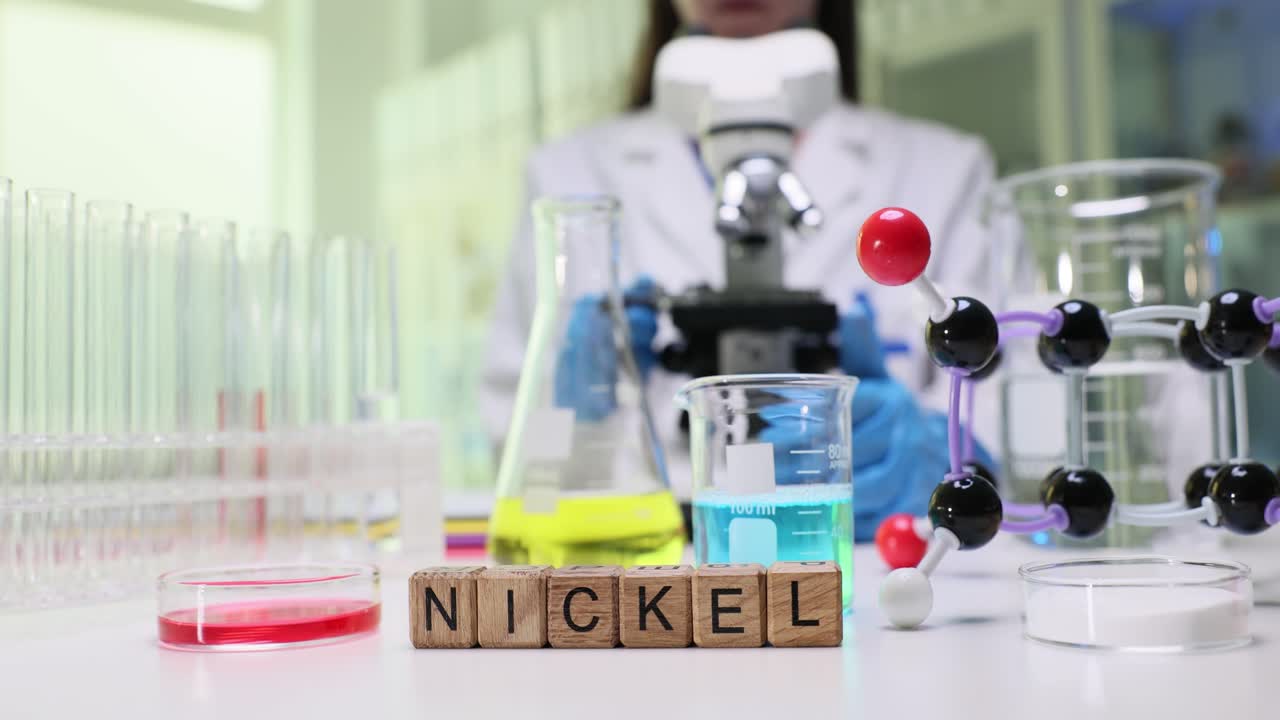 Scientist conducting experiments in a chemistry laboratory with 'NICKEL' blocks