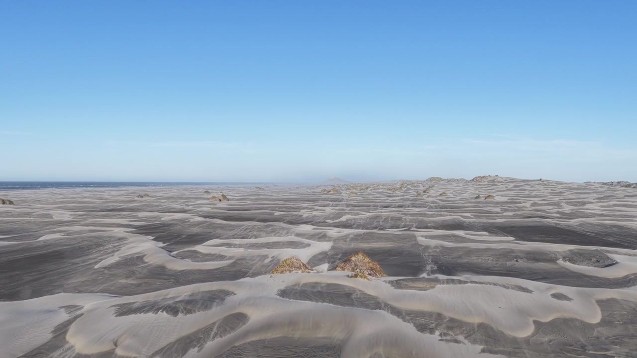 El viento mueve arena fina a través de dunas costeras estériles en la Isla Sur de Nueva Zelanda. Paisaje minimalista y desolado con patrones texturizados, terreno seco y una atmósfera natural remota.