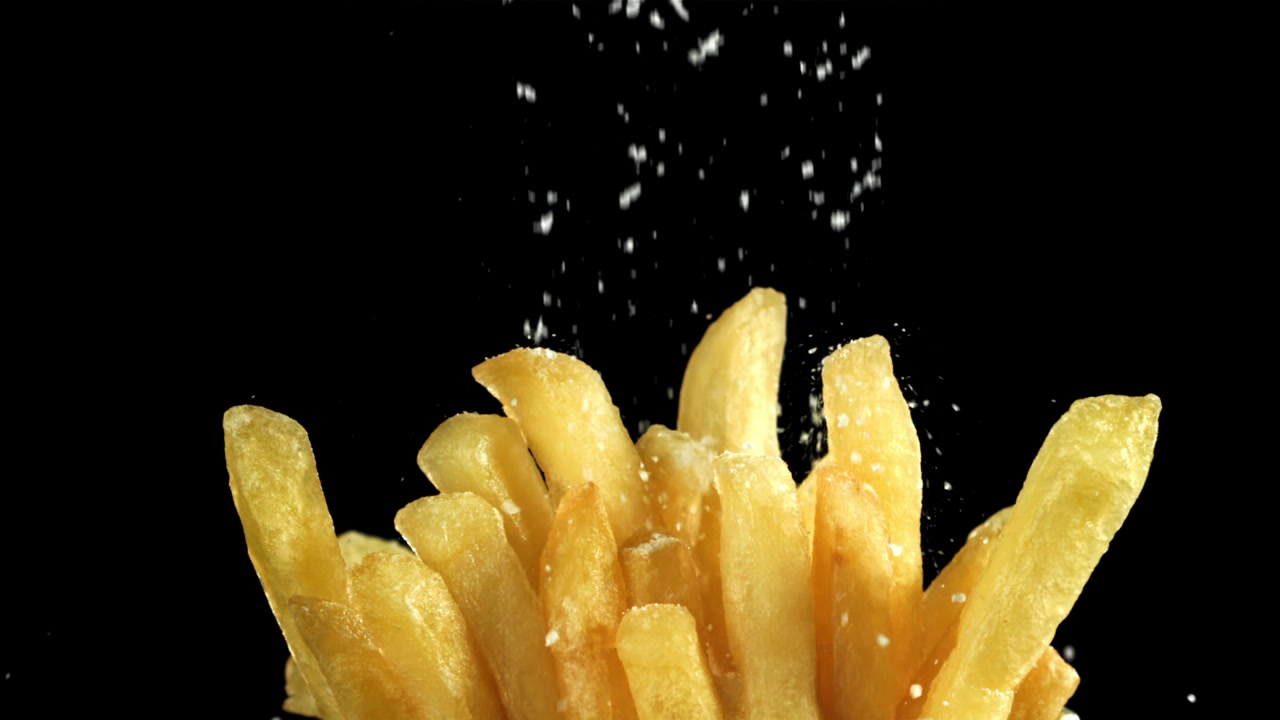 Close-up of Salt Sprinkling on Golden French Fries