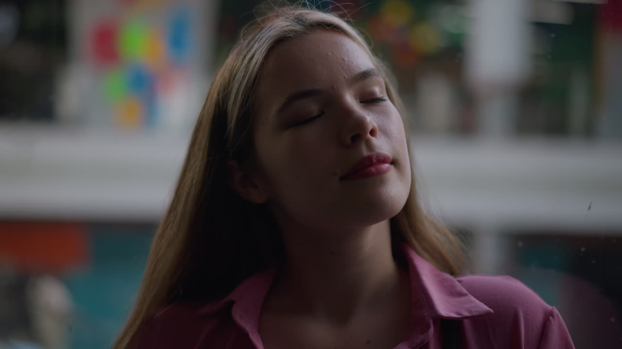 dama de vestido rosado está de pie con los ojos cerrados, mirando relajado y pacífico, su rostro está suavemente iluminado, con una expresión feliz, el fondo es borroso, con estructuras coloridas