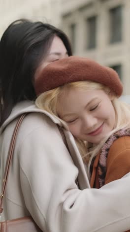 two women hugging on a city street