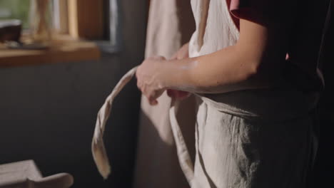 woman tying an apron in a rustic kitchen