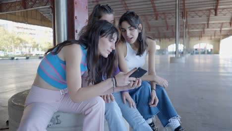 three young women looking at a smartphone outdoors