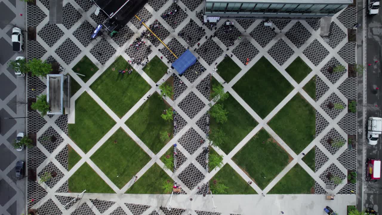 Top-down view of busy City plaza with contemporary geometric brick pattern, people walking
