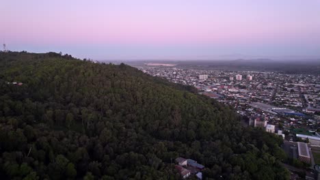 sobrevuela el cerro ñielol y la ciudad de temuco con un atardecer morado y el volcan llaima de fondo