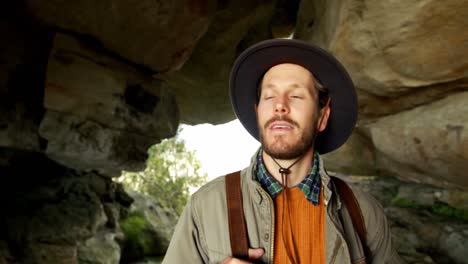 male hiker standing with backpack in the cave 4k