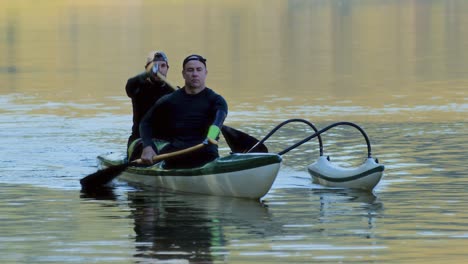 two men paddling an outrigger canoe